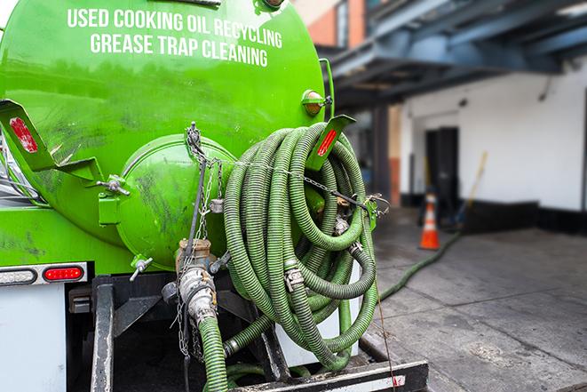 a technician pumping a grease trap in a commercial building in Armada